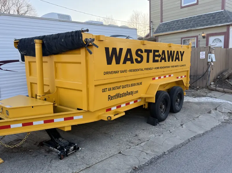 Waste Away 15-yard dumpster on a residential driveway, tongue jack and wheel chocks in place